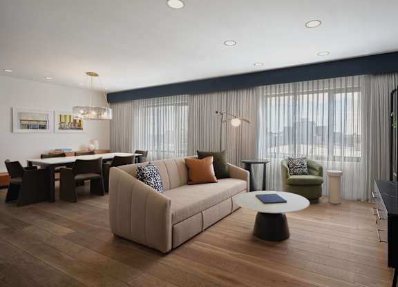 A modern living room with a beige sofa and a wooden floor.
