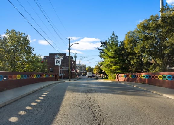 a city street with a fence and trees on the side of the road