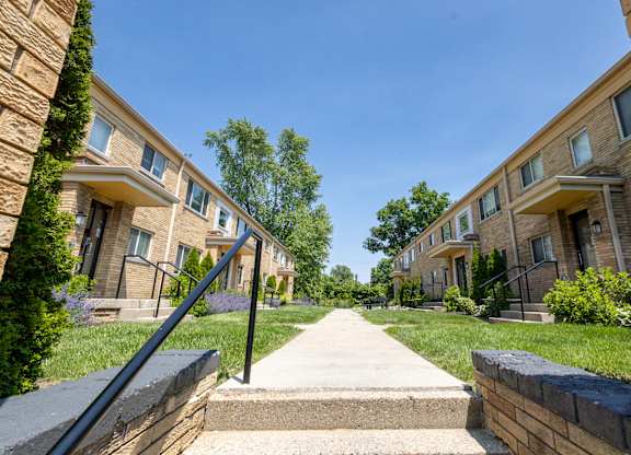 Ground-level perspective of landscaped courtyard and classic brick facades at Monon Court apartments, near Monon Trail access