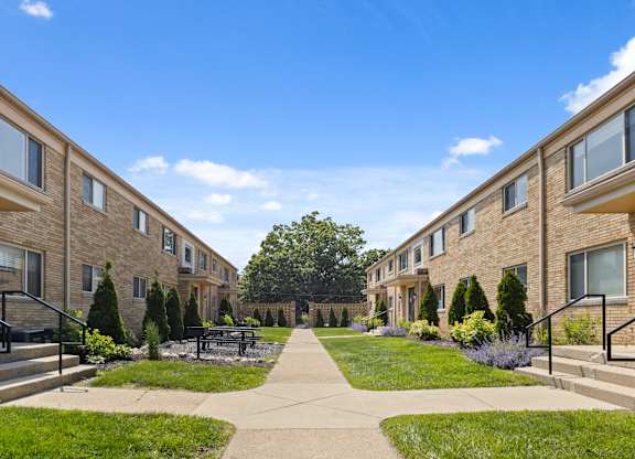 Courtyard view of Monon Court vintage apartment buildings with lush landscaping and walkways in Broad Ripple neighborhood
