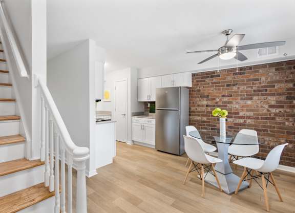 Contemporary kitchen and dining area at Monon Living in Broad Ripple featuring exposed brick, stainless steel appliances, and direct trail access via the Monon.