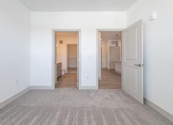 a living room with white walls and a door to a kitchen