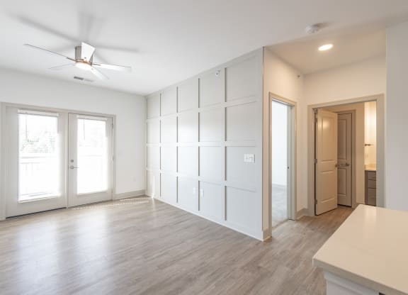 an empty living room with white walls and a ceiling fan