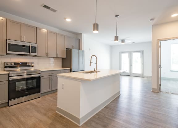 an open kitchen and living room with an island and stainless steel appliances