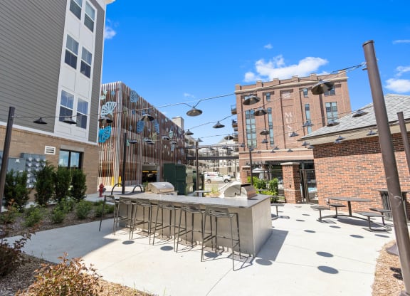 a patio with a bar and chairs in front of a building