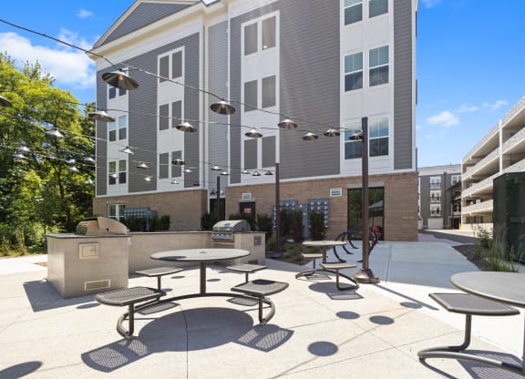 a patio with tables and chairs in front of an apartment building