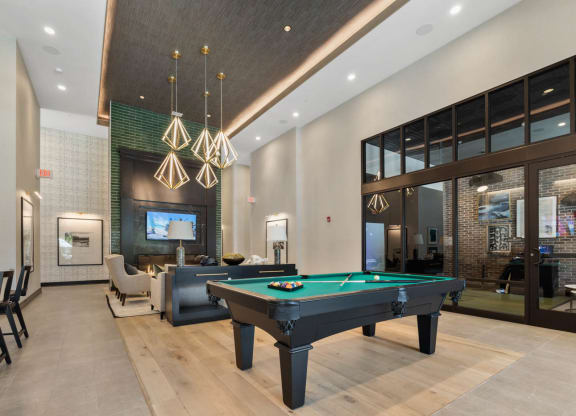 a pool table in the lobby of a clubhouse with a tv