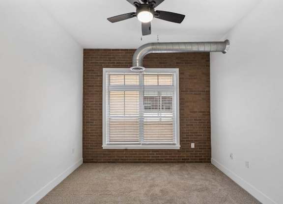 A room with a ceiling fan and a window with blinds.at The Foundry, South Bend Indiana