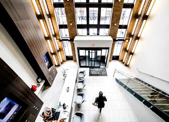 a woman walking through the lobby of a building at The Foundry, South Bend, 46617