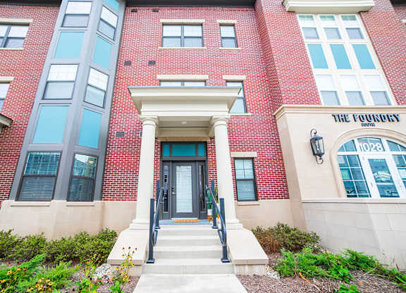 a red brick building with a glass door and steps in front of it at The Foundry, South Bend Indiana
