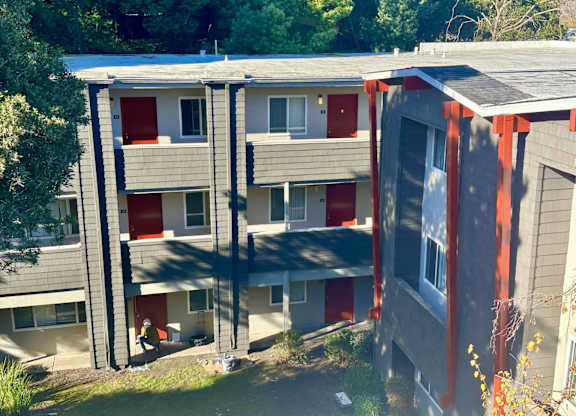 A building with grey and red exterior and a balcony.