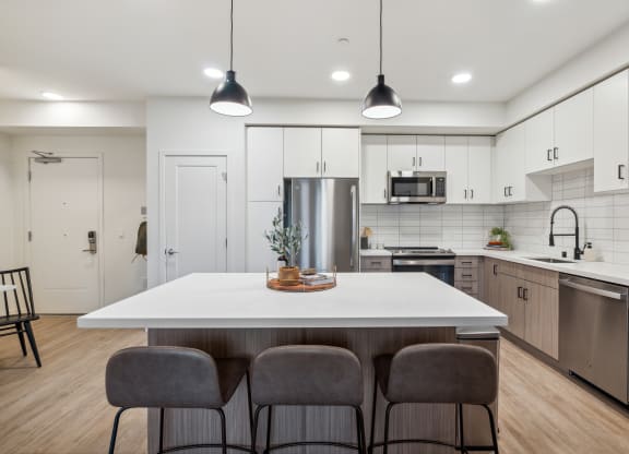 an open kitchen with a large white island with four chairs at 38° NORTH, California