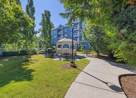 A park with a bench and a building in the background.