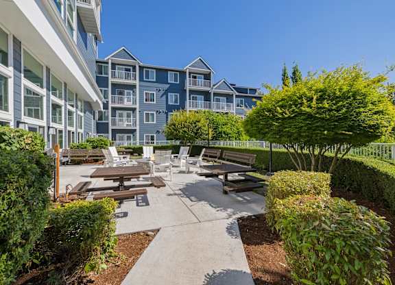 A courtyard with benches and a fence in front of apartment buildings.