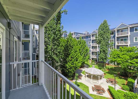 A balcony overlooks a courtyard with a gazebo and trees.