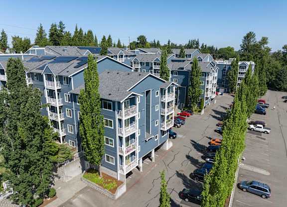 A parking lot in front of a row of apartment buildings.