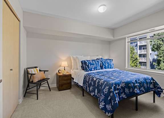 A bedroom with a bed, nightstand, and chair.
