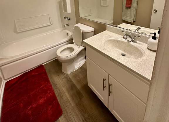 A white toilet sits in a bathroom next to a sink.