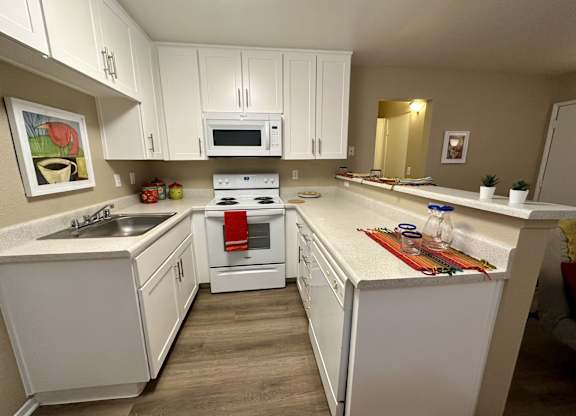 A white kitchen with a stove top oven and a microwave.