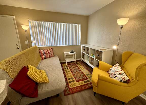 A living room with a grey couch, yellow armchair, and a white side table.