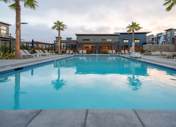 a swimming pool with palm trees and a building in the background at 38° NORTH, California, 95404