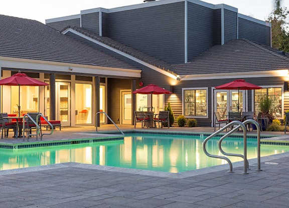 A house with a pool and a red umbrella.