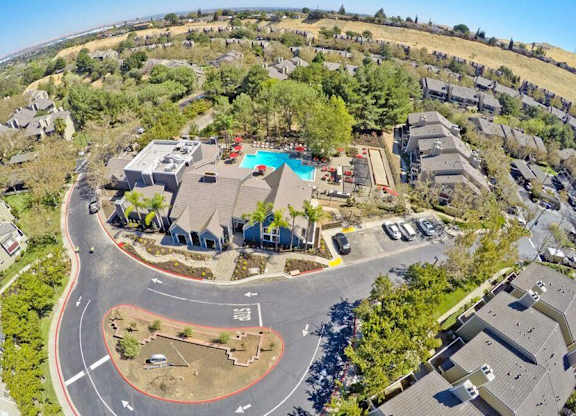 An aerial view of a neighborhood with a large house and a pool in the center.