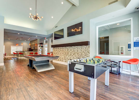 A room with a foosball table and a shaggy rug.