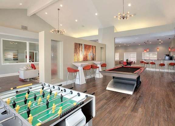 A foosball table is in the middle of a room with a couch and chairs.