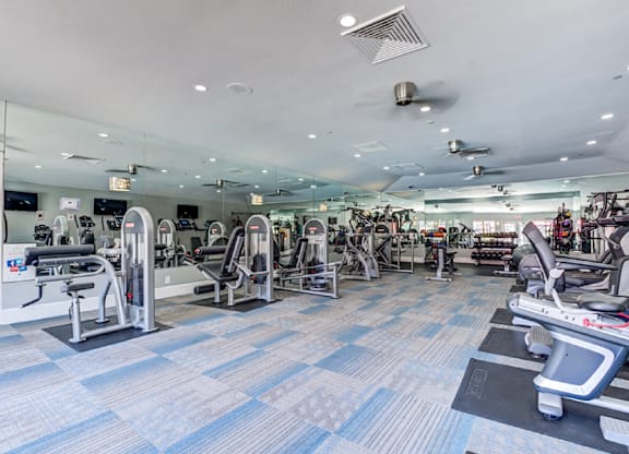 A gym with a variety of equipment including treadmills, weights, and exercise machines.