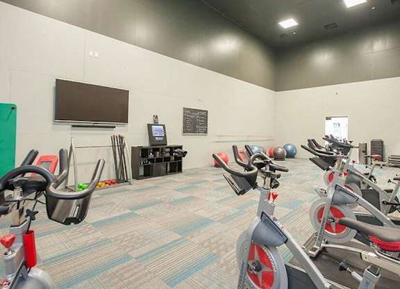 A gym with exercise bikes and a television on the wall.