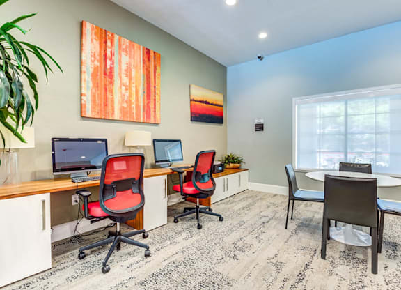 A room with a desk, chairs, and a computer.