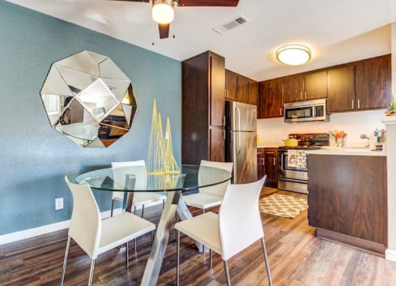 A modern kitchen with a glass dining table and chairs.