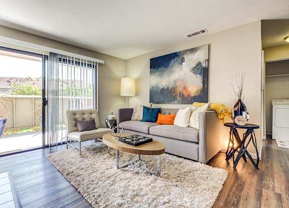 A modern living room with a grey sofa, a coffee table, and a painting on the wall.