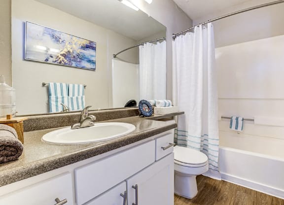 A bathroom with a white tub, sink, and toilet.