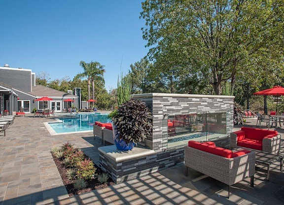 A poolside area with a stone bench and a glass wall.