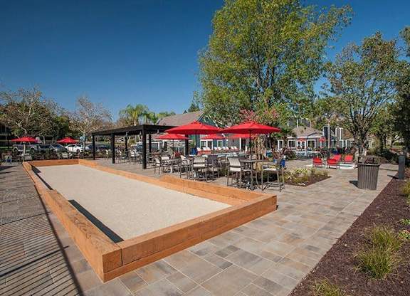 A shuffleboard court is surrounded by tables and chairs.