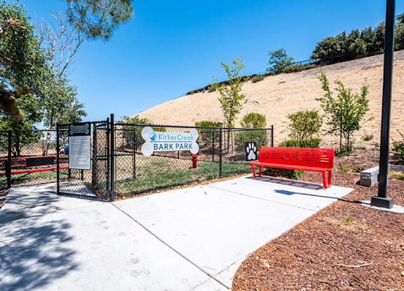 A sign for Kirby Cove Bark Park is displayed in front of a fence.