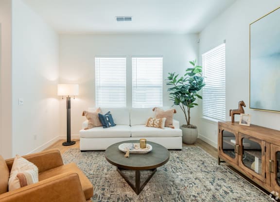 Furnished Living Room with Wood-Style Flooring, a Large Rug, Three Windows, and Stylish Decor at Crocker Village – Single Family Homes, Sacramento California ? 