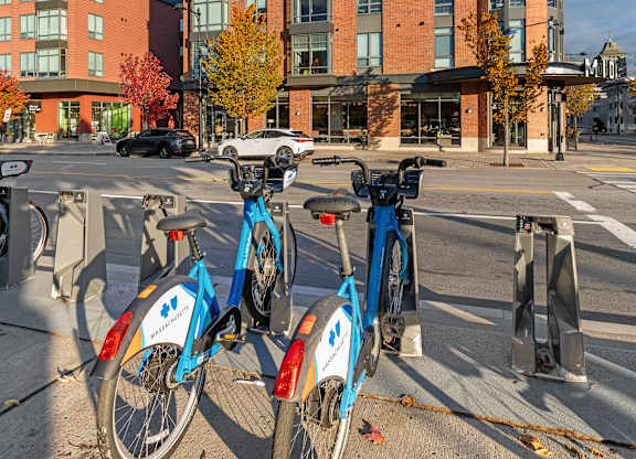 Two bikes are parked on the sidewalk in front of a building. at Trio Newton Apartments, Massachusetts