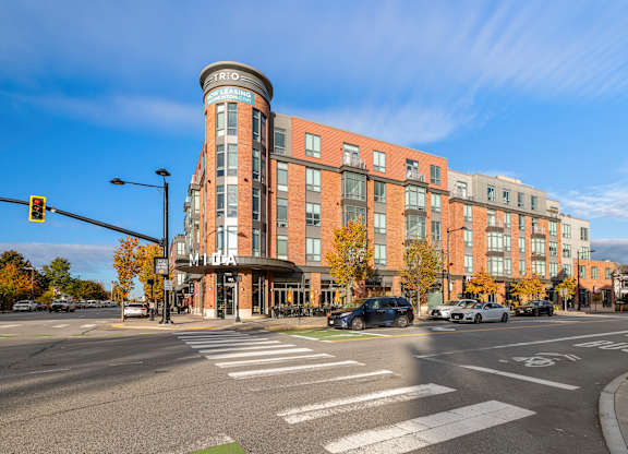 A street view of a city intersection with cars and a traffic light. at Trio Newton Apartments, Newton, Massachusetts