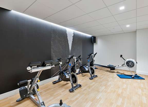 A room with exercise equipment and a wooden floor. at Trio Newton Apartments, Newton