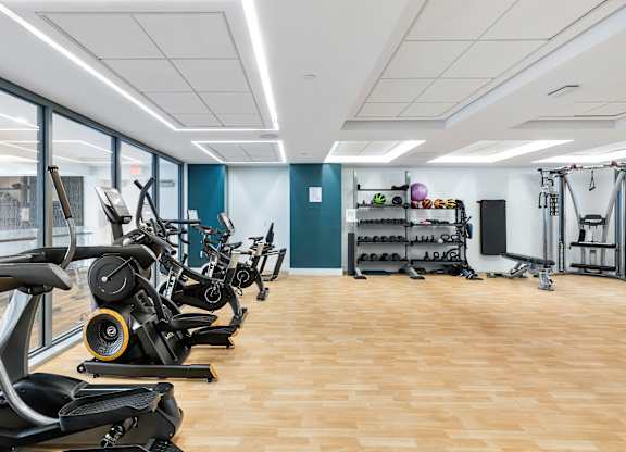 A gym with treadmills, elliptical machines, and other exercise equipment at Trio Newton Apartments, Newton, 02460
