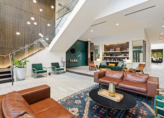 A living room with a brown leather couch and a black coffee table at Trio Newton Apartments, Massachusetts