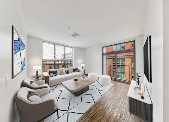 A living room with a grey sofa and a black and white rug. at Trio Newton Apartments, Apartments, Newton, MA
