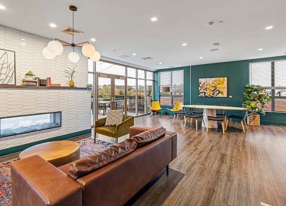 A modern living room with a fireplace and a large brown sofa. at Trio Newton Apartments, Apartments, Newton, MA