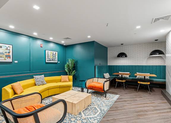 A brightly colored living room with a yellow couch and a wooden coffee table. at Trio Newton Apartments, Newton, MA, 02460