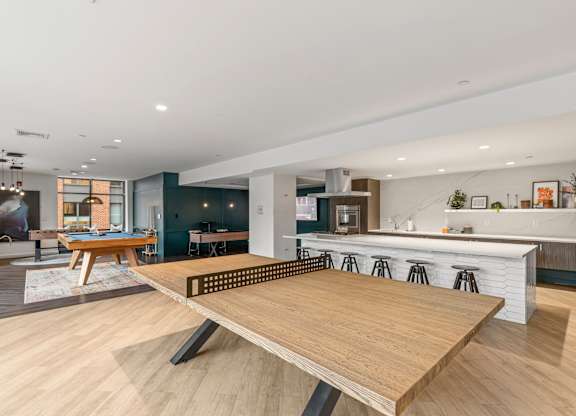 A modern kitchen with a wooden table in the middle. at Trio Newton Apartments, Newton, MA, 02460