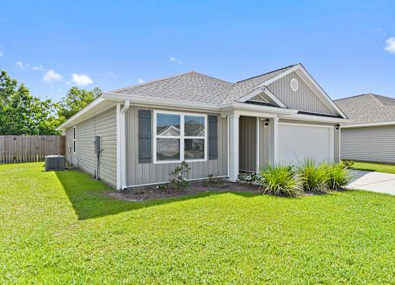 Single-story home with gray siding, dark shutters, and green lawn.