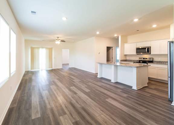 an empty living room and kitchen with wood flooring